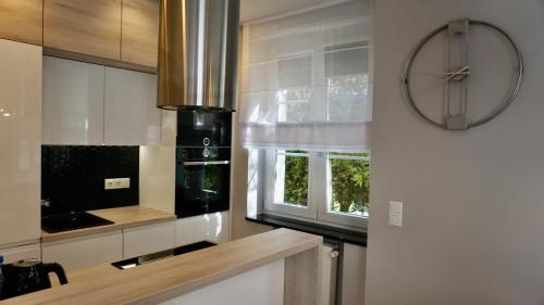 a kitchen with a stove and a clock on the wall at Apartament w samym sercu Opola 2 in Opole