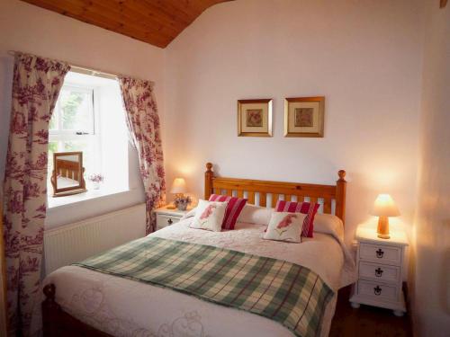 um quarto com uma cama com almofadas vermelhas e uma janela em Kizzie Cottage Killorglin by Trident Holiday Homes em Killorglin