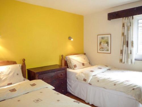two beds in a room with yellow walls at The Lodge Rossbeigh by Trident Holiday Homes in Glenbeigh