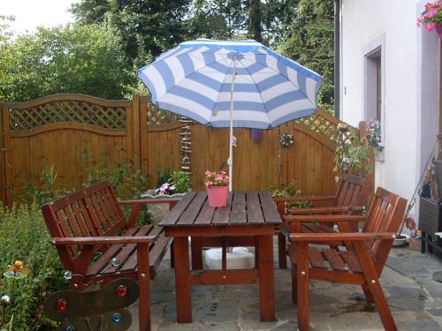 a picnic table with an umbrella and two chairs at Ferienhaus am Geißnhof in Weiden