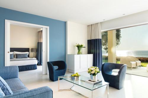 un soggiorno con 2 sedie blu e un tavolo in vetro di Sani Club a Sani Beach