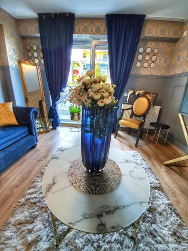 a blue vase with flowers on a table in a living room at Portobella Airport Aparthotel - Self Check in in Otopeni