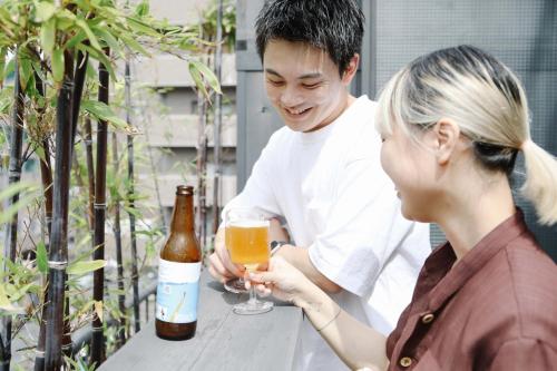 een man en een vrouw met een glas bier bij Sunny Day Hostel in Takamatsu