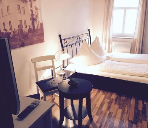 ein Schlafzimmer mit einem Bett, einem Tisch und einem Stuhl in der Unterkunft Dorfschänke DEGGENDORF Hotel & Apartmenthaus in Deggendorf