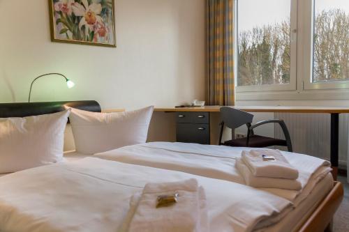 a hotel room with a bed and a desk and a window at Seepark Hotel am Wandlitzsee in Wandlitz