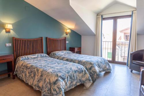 two beds in a hotel room with a window at Apartamento Abuela Benita in Cebreros