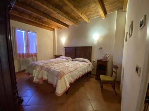 a bedroom with a bed and a chair and a window at Agriturismo la Chiusola in Ozzano dell'Emilia