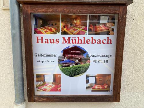 een poster in een houten frame op een muur met een huis bij Hotel Haus Mühlebach in Ernen