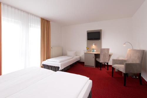 a hotel room with a white bed and a desk at ACHAT Hotel Frankenthal in der Pfalz in Frankenthal