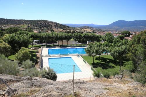 a swimming pool in a field with mountains in the background at Apartamento Abuela Benita in Cebreros