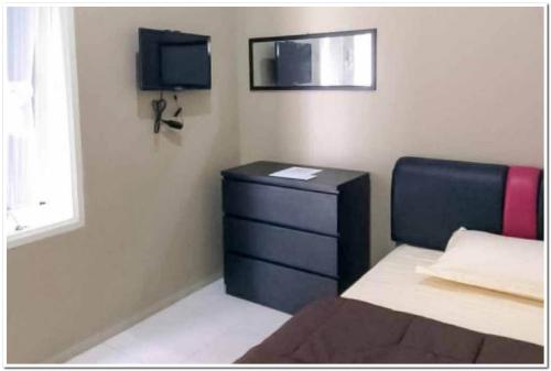 - une chambre avec un lit, une commode et une télévision dans l'établissement Syukur Guesthouse Syariah RedPartner, 