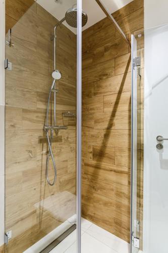 a shower in a bathroom with a wooden wall at Apartmán na golfu in Čeladná