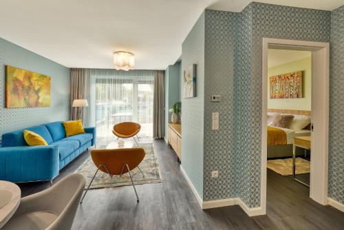 a living room with a blue couch and a bedroom at Club Luxury Apartman in Sárvár