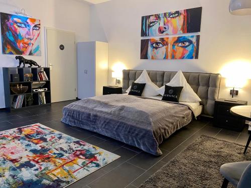 a bedroom with a bed and a couch and paintings at GelsenDesign - Gemütliches Studio-Apartment in Gelsenkirchen