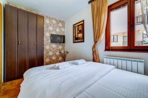 a bedroom with a large white bed and a window at Zlatiborski Konaci in Zlatibor