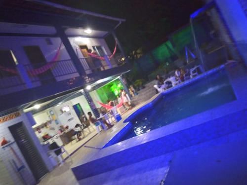 a group of people sitting around a swimming pool at night at Pousada Sossego Salinas in Salinópolis