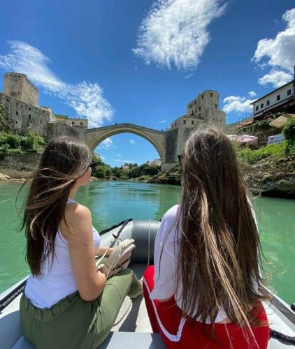 two girls in a boat on a river in front of a castle at Villa Zigana in Mostar