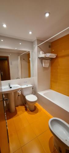 a bathroom with a toilet and a sink and a tub at Apartamentos Laredo-Playa in Laredo