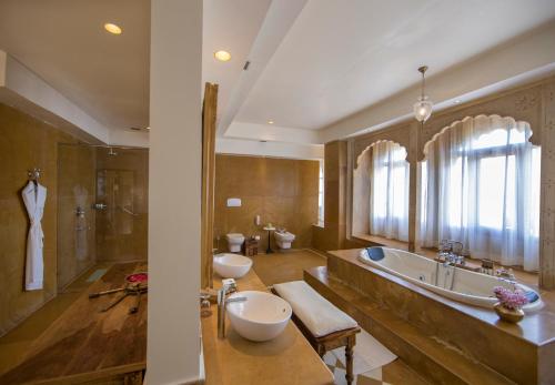 uma casa de banho com 2 lavatórios, uma banheira e um chuveiro em Suryagarh Jaisalmer em Jaisalmer