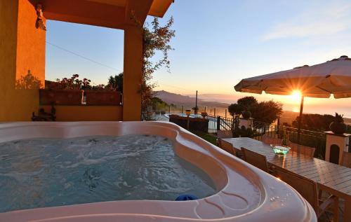 einen Whirlpool auf einer Terrasse mit einem Tisch und einem Sonnenschirm in der Unterkunft Bellavista Etna in Mascali