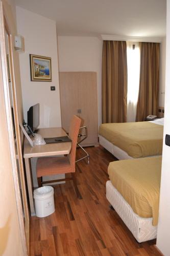 a hotel room with two beds and a desk with a computer at Tricolore Hotel in Gaida