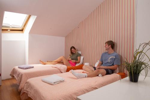 dwoje osób siedzących na łóżkach w pokoju w obiekcie Onefam Madrid w Madrycie