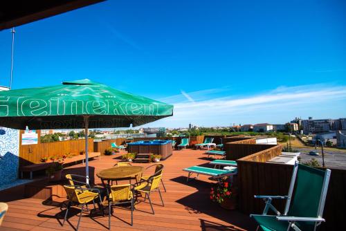 eine Terrasse mit Tischen und Stühlen und einem grünen Sonnenschirm in der Unterkunft Best Western Plus Lido Hotel in Timişoara