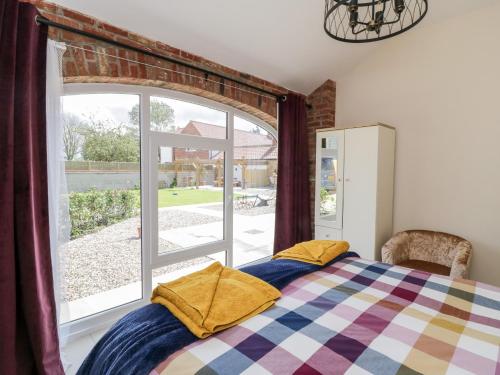 a bedroom with a bed and a large window at Plough Cottage in Great Driffield