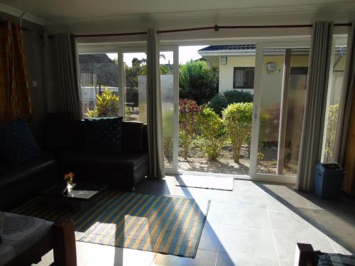 a living room with a couch and sliding glass doors at IDC Guest House in Bagamoyo
