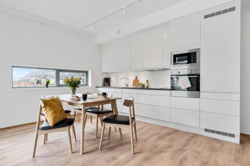 cocina blanca con mesa de madera y sillas en BJØRVIKA APARTMENTS, Damsgård Area, Bergen city center, en Bergen