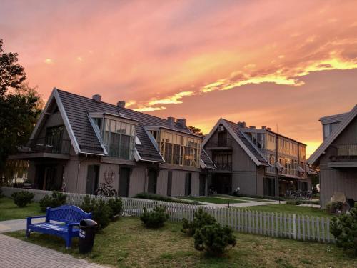 uma casa com um banco azul em frente em Lagoon Attic Apartment Pervalka em Pervalka