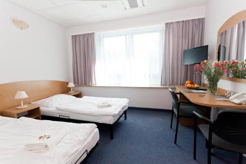 a hotel room with two beds and a desk at Kompleks Milenium in Kołobrzeg