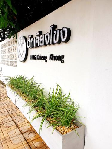 a sign on the side of a building with plants at ฮักเคียงโขง HUG Khieng Khong Nongkhai Hostel in Nong Khai