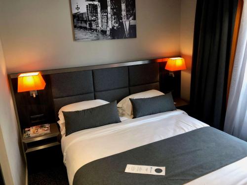 a hotel room with a bed and two lamps at Best Western Empire Elysees in Paris