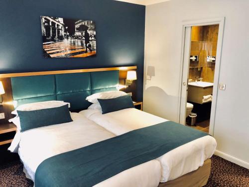 a bedroom with a large bed with a green headboard at Best Western Empire Elysees in Paris