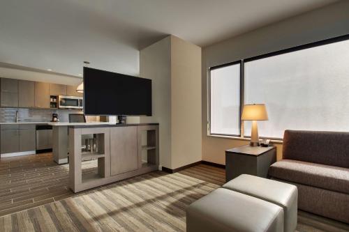 a living room with a couch and a flat screen tv at Hyatt House Oak Brook in Oak Brook
