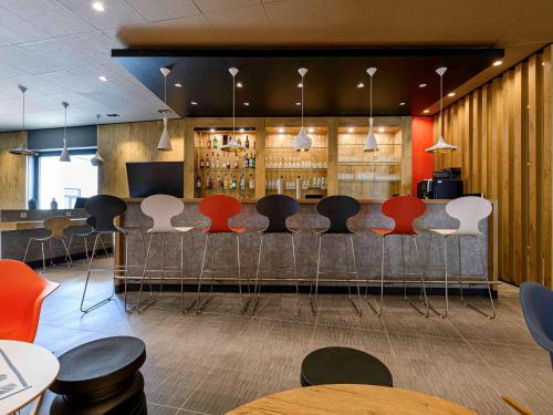a bar with red and white chairs in a restaurant at ibis Regensburg Zentrum in Regensburg