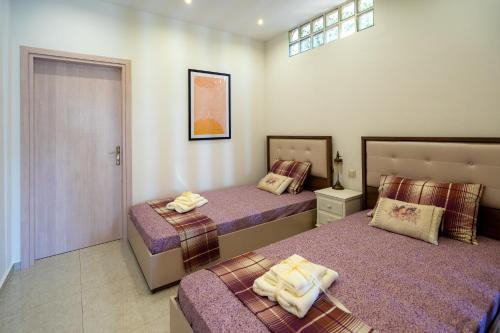 a bedroom with two beds with purple sheets at Meteoron Theasis in Kalabaka