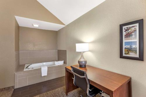 Comfort Inn & Suites Greeley في غريلي: غرفة بها مكتب مع مصباح ومغسلة