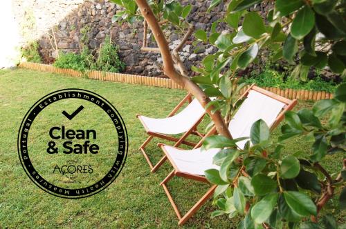 two chairs sitting in the grass next to a sign at Verde'Água Family Home in Mosteiros