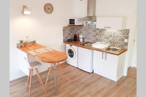 a kitchen with a table and a washing machine at Studio hyper centre avec balcon in Châteauroux