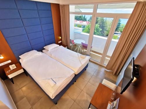 a small bedroom with a bed and a large window at Hotel & Spa Tino Sveti Stefan in Ohrid