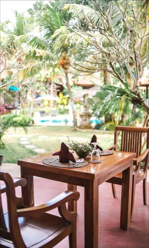 een houten tafel met een hoed en twee stoelen bij Ubud Hotel & Cottages in Malang