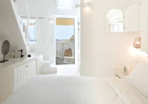 a white room with a bed and a mirror at Dana Villas & Infinity Suites in Firostefani