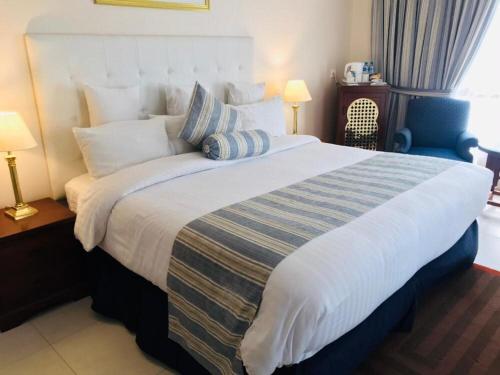 a bedroom with a large bed with a blue chair at Beach Luxury Hotel in Karachi