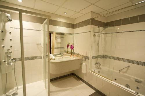 y baño con bañera, lavamanos y ducha. en One Pavilion Luxury Serviced Apartments en Manama