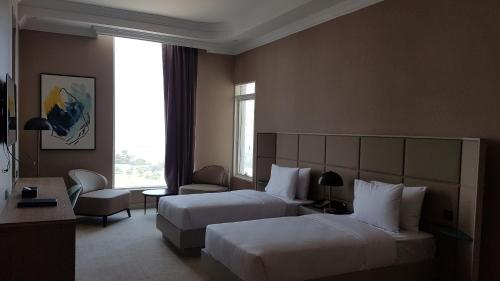a hotel room with two beds and a window at Horizon Manor Hotel in Doha