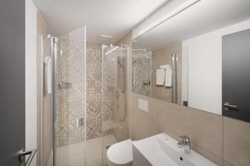 a bathroom with a shower and a toilet and a sink at Brera Serviced Apartments Ulm in Ulm