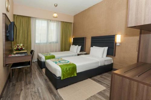 a hotel room with two beds and a television at Oasis Deira Hotel in Dubai