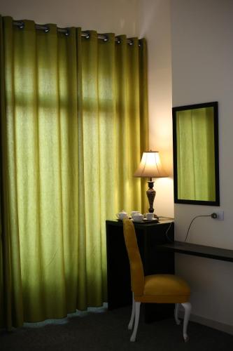 a room with a green curtain and a chair and a lamp at City Citadel Hotel,Amman in Amman